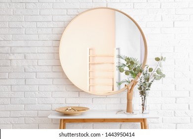 Big round mirror, table with jewelry and decor near brick wall in hallway interior - Shutterstock ID 1443950414