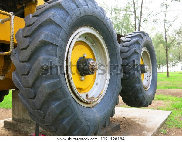 Big rubber tire\
with heavy equipment in\
park.