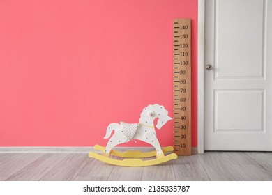 Big Ruler For Height Measuring, Rocking Horse And White Door Near Color Wall