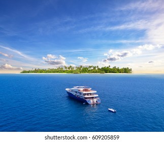 Big safari luxury yacht sailing on ocean in Maldives, tropical island on background. Concept of travel vacation and vessel trip