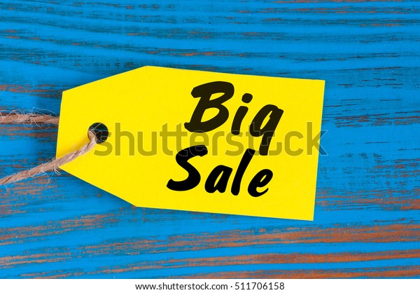 Big Sale tag on blue wooden background. Sales,\
discount, advertising, marketing price tags for clothes,\
furnishings, cars, food