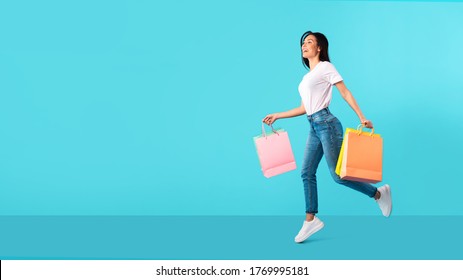 Big Sales Concept. Excited Girl Running With Shopping Bags Isolated Over Blue Turquoise Studio Wall, Copy Space