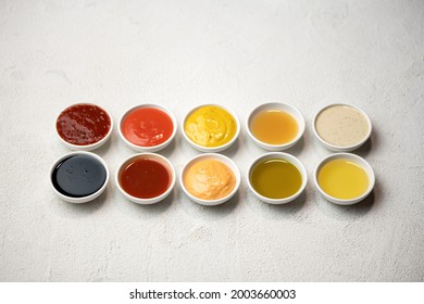 Big Set of colored sauces in Crockery. Different sauces, mayonnaise, mustard, soy sauce, oil and ketchup on white background. Top side view. Tasty food. Kitchen utensils.