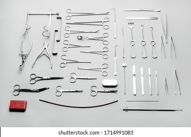 Big set of different medical instruments used for surgical operations, for abdominal surgery and other medical procedures. Made of stainless steel, sorted by tool type, laid out on a gray background