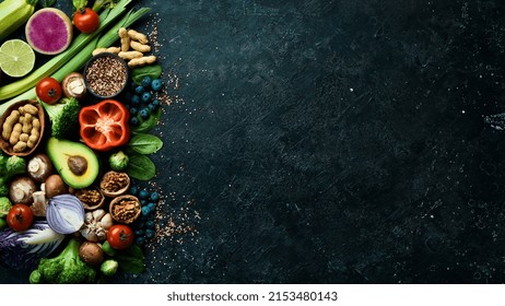 Big set of organic food. On a black chalkboard. Fresh raw fruits, vegetables, nuts, mushrooms and berries. On a black stone background. Top view. Copy space. - Powered by Shutterstock