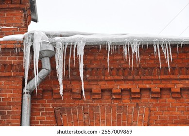 Big sharp icicles on roof of residential house, icy drain pipe. Icicles hanging on roof, risk for pedestrians in winter season. Icicle on rooftop of the building. Icicles hanging from the roof - Powered by Shutterstock