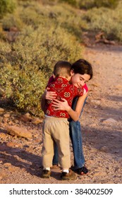 A Big Sister Gives Her Little Brother A Comforting Hug When He Gets Tired On A Desert Hiking Trail.  It Is Late Afternoon And Looks Peaceful And Sweet.