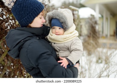 Big Sister And Her Toddler Brother Having Fun Outdoors. Teenage Girl Holding Her Sibling Boy On Winter Day. Kids During Winter Break. Children Exploring Nature Together.