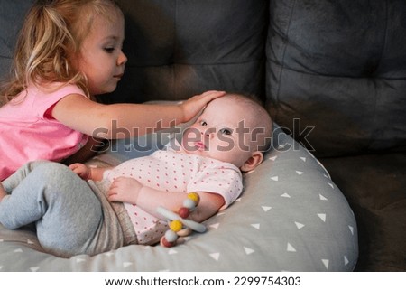 Big sister is looking at little sister. Sibling relationship. Sister's love. New baby at home