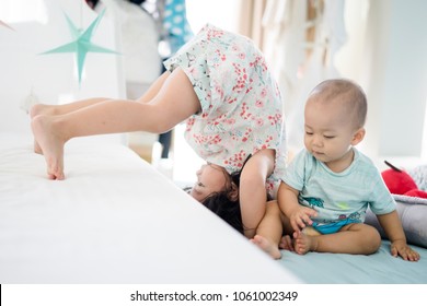 Big Sister Somersault Or Forward Roll  With Her Baby Brother.Toddler Kid Meeting New Sibling.Cute Girl And New Born Baby Boy Relax In A Sofa Bed.Family With Children At Home.