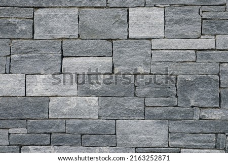 Big and small Bricks in a grey Stone Wall