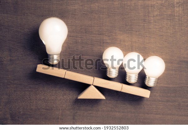 Big and small light bulbs on scale\
symbol, group of small light bulbs have more weight than a lone big\
light bulb, business size or teamwork\
concept