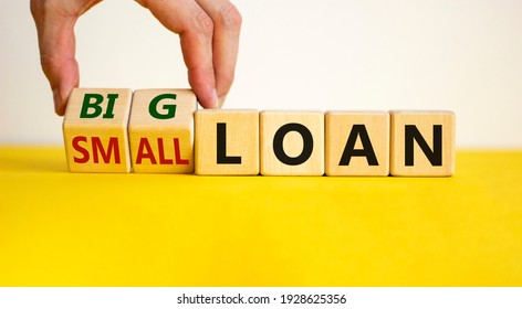 Big or small loan symbol. Businessman turns a wooden cube and changes words 'small loan' to 'big loan'. Beautiful yellow table, white background, copy space. Business and big or small loan concept. - Shutterstock ID 1928625356