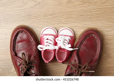 Big And Small Shoes On Wooden Background