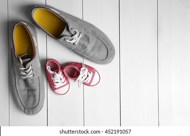 Big and small shoes on wooden background