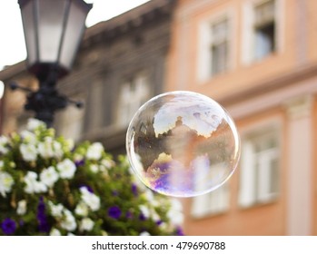 Big soap bubble flies through air in city soft focus