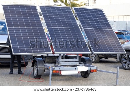 Big solar panels array at trailer portable power equipment technology in a car parking lot.