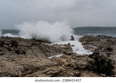 Big splash from wave crashing on the rocky shore of Antibes