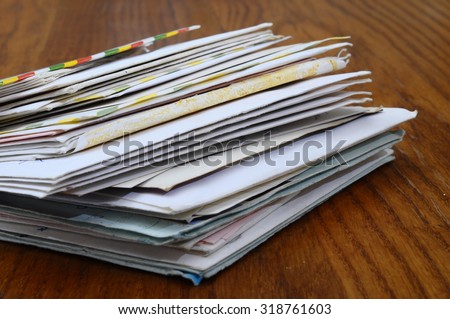 Big stack of mails, pile of papers, or heap of letters waiting on wooden table