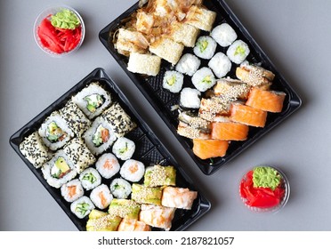 Big Sushi Rolls Set In Black Plastic Box For Take Away On Gray Background. Top View