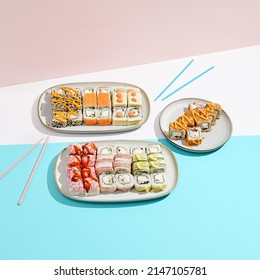 Big sushi set on ceramic dishware with coloured chopsticks. Trendy set of maki sushi in minimal style. Modern japanese menu concept. Maki sushi assorted on coloured background - Shutterstock ID 2147105781