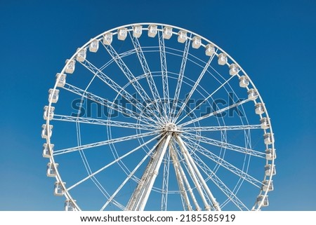 Big, tall white Ferris wheel in front of a perfect blue sky at the oceanfront in Marseille, France. Happy summer vacation feelings. 
