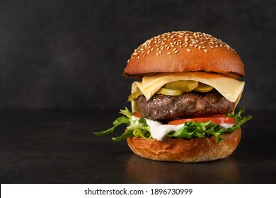 Big tasty burger with beef cutlet on a black stone background