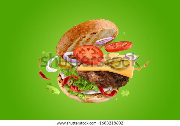 Big tasty hamburger with flying elements.\
Flying burger. Green\
background.