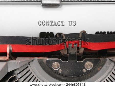 big text CONTACT US with Black ink on white paper in the typewriter  ideal for website