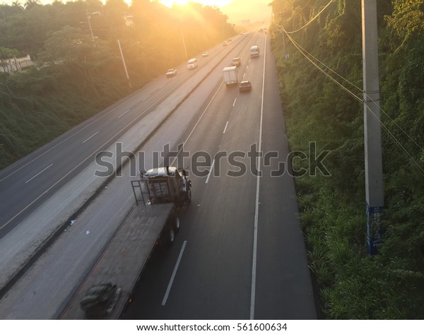 A\
big trailer driving on the highway to the rising\
sun.
