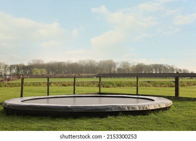 Big trampoline near wooden fence on green lawn outdoors - Shutterstock ID 2153300253