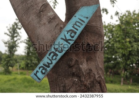 a big tree with a sign attached that says care for us, in Indonesian namely 