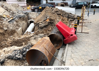 Big Trench On The Road With A Pipe, The Process Of Repair Or Replacing Of Water Pipes With Safety Fencing. Repair Of Broken Roads And Underground Water Pipes In The City
