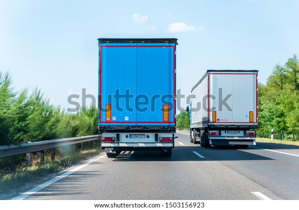 Big
truck driving fast on the asphalt road in sunny day in countryside
landscape.Fast driving lorry  overtaking another truck.Highway
view.Clear blue sky.Cargo transportation
concept.