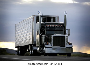 big truck driving on a highway with cloudy sky in background