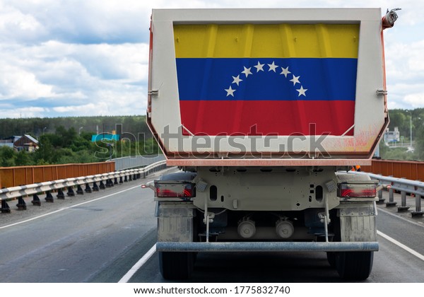 Big  truck with the national flag of  Venezuela moving\
on the highway, against the background of the village and forest\
landscape. Concept of export-import,transportation, national\
delivery of goods 