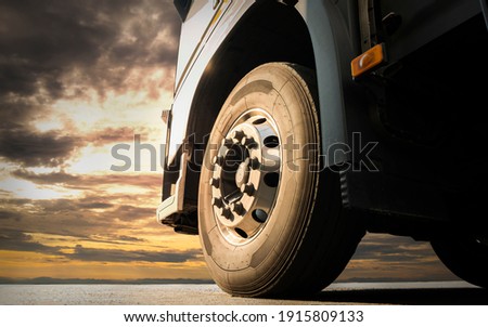 Big truck wheel tires. Semi truck parked at sunset sky. Industry freight truck transportation. Auto service shop