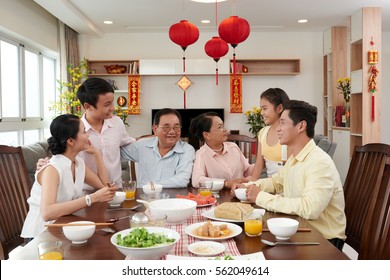 Big Vietnamese Family Gathered At Tet Table; Couplets With Best Wishes For Coming Year In The Background