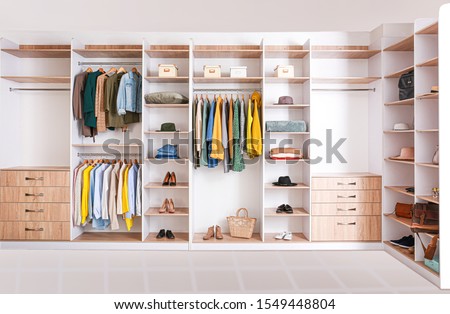 Big wardrobe with clothes in dressing room
