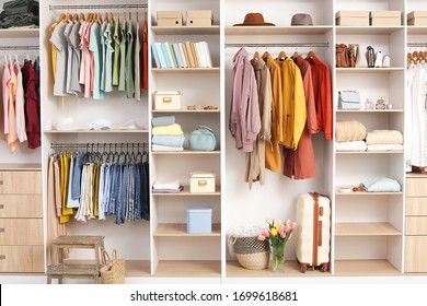 Big wardrobe with different clothes and accessories in dressing room