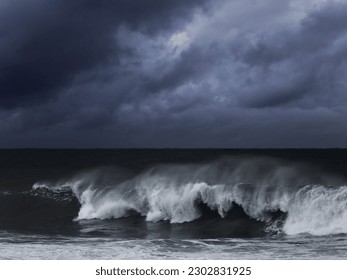 Big wave against dark dramatic enhanced sky. Toned blue.