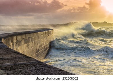 Big waves crushing on curved stone pier, on stormy weather with vivid sunset, big tide, Saint Malo, France. - Powered by Shutterstock