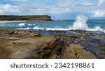 Big waves splash at the rocky plateau at Big Marley Beach in Royal National Park, NSW, Australia. View of a rocky headland and giant waves.