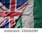 big waving national colorful flag of great britain and national flag of nigeria . macro