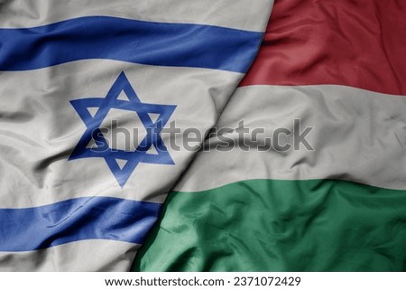 big waving national colorful flag of israel and national flag of hungary . macro