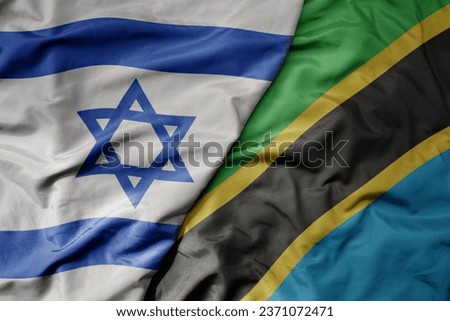big waving national colorful flag of israel and national flag of tanzania . macro