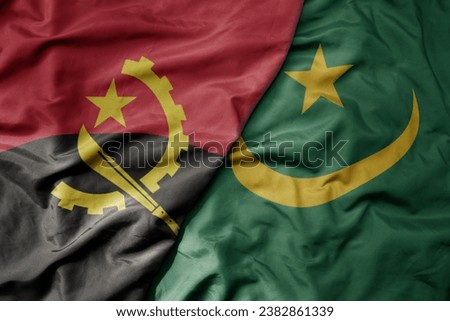 big waving national colorful flag of angola and national flag of mauritania . macro