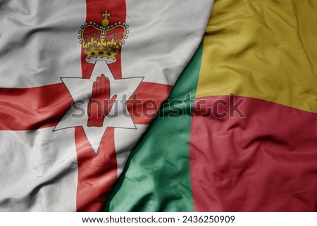 big waving national colorful flag of benin and national flag of northern ireland . macro