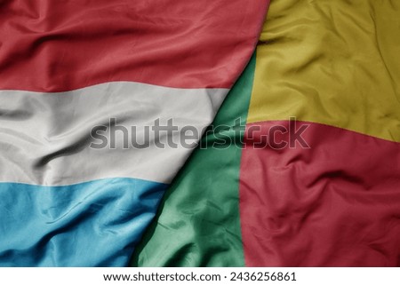 big waving national colorful flag of benin and national flag of luxembourg . macro