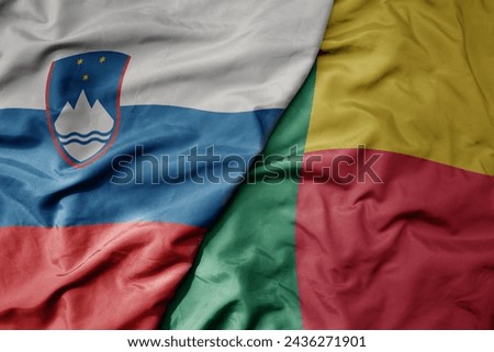 big waving national colorful flag of benin and national flag of slovenia. macro